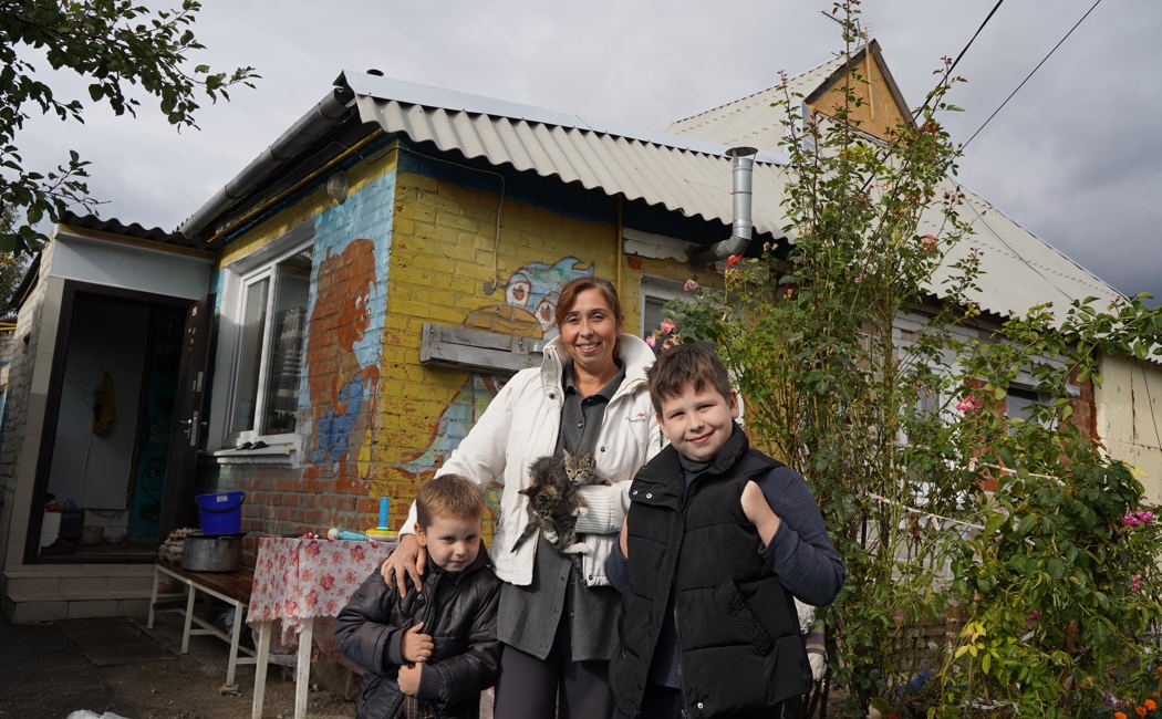 Nataliia and her children in front of their house which UNHCR helped repair