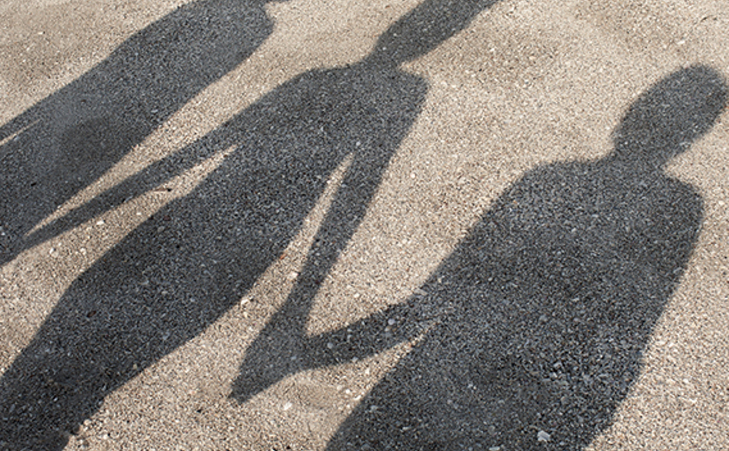 Three women's shadows cast on to the pavement, walking hand in hand 