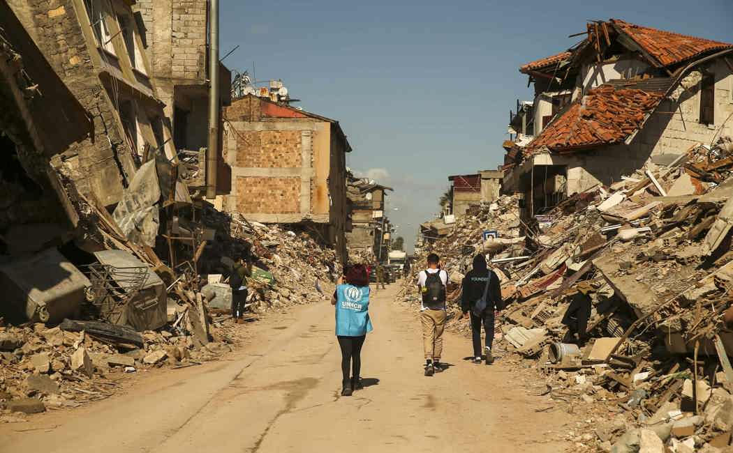 A UNHCR staff member walks amidst the devastation of the earthquakes in Hatay city.