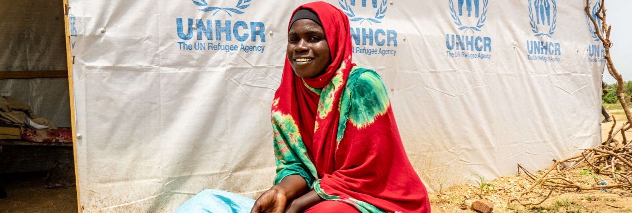 Sudanese refugee Hawa Issat in front of her temporary shelter 