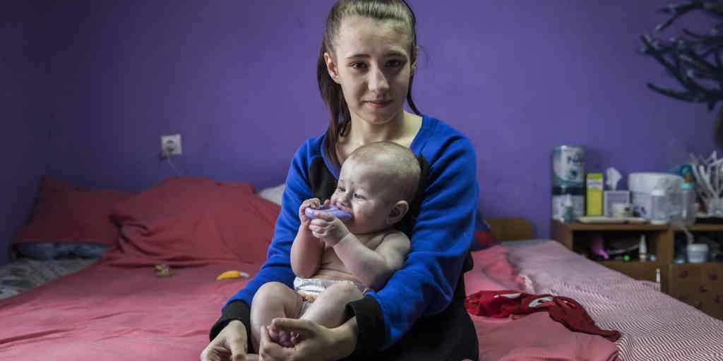 Valeria sits on her bed at a shelter for displaced people in Ukraine with her one-year-old son, David.