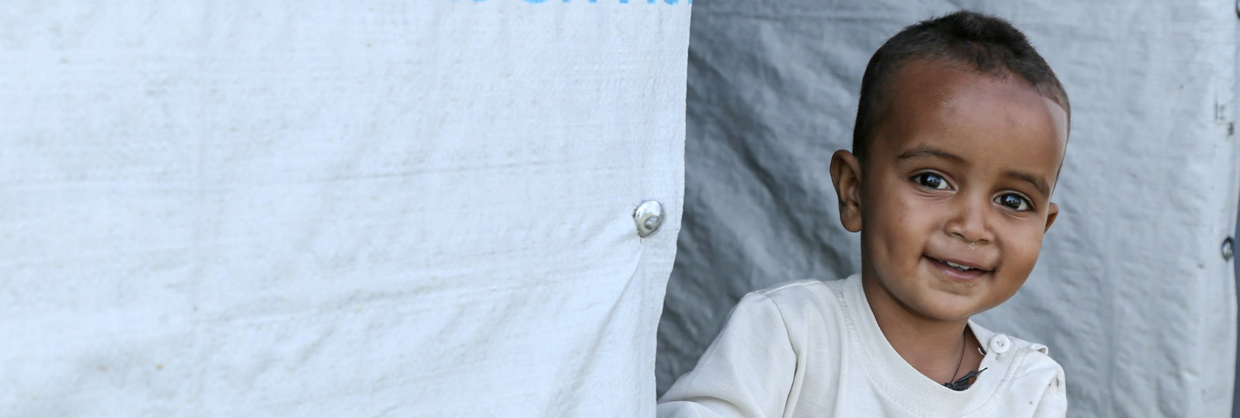 Ethipian refugee boy looks out from UNHCR tent