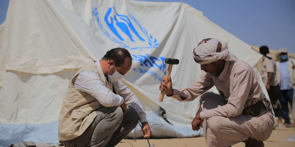 In Yemen, two displaced men in Marib build a tent.
