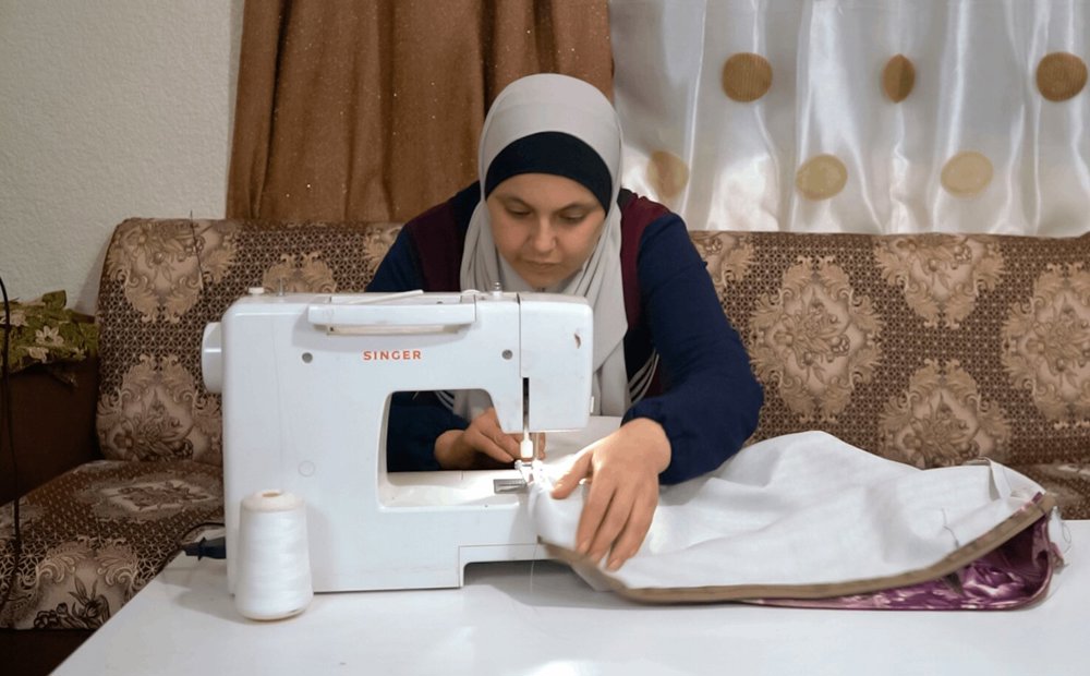 Zuzan works at her sewing machine at her home in Jordan