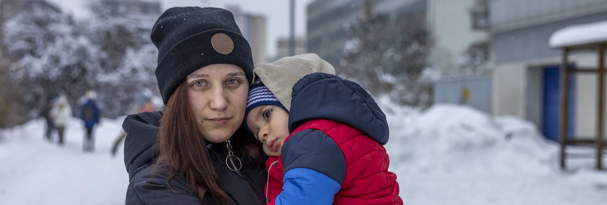 Woman holds child in the snow. Kateryna fled her hometown of Kryvyi Rih in southern Ukraine on 6 March. 