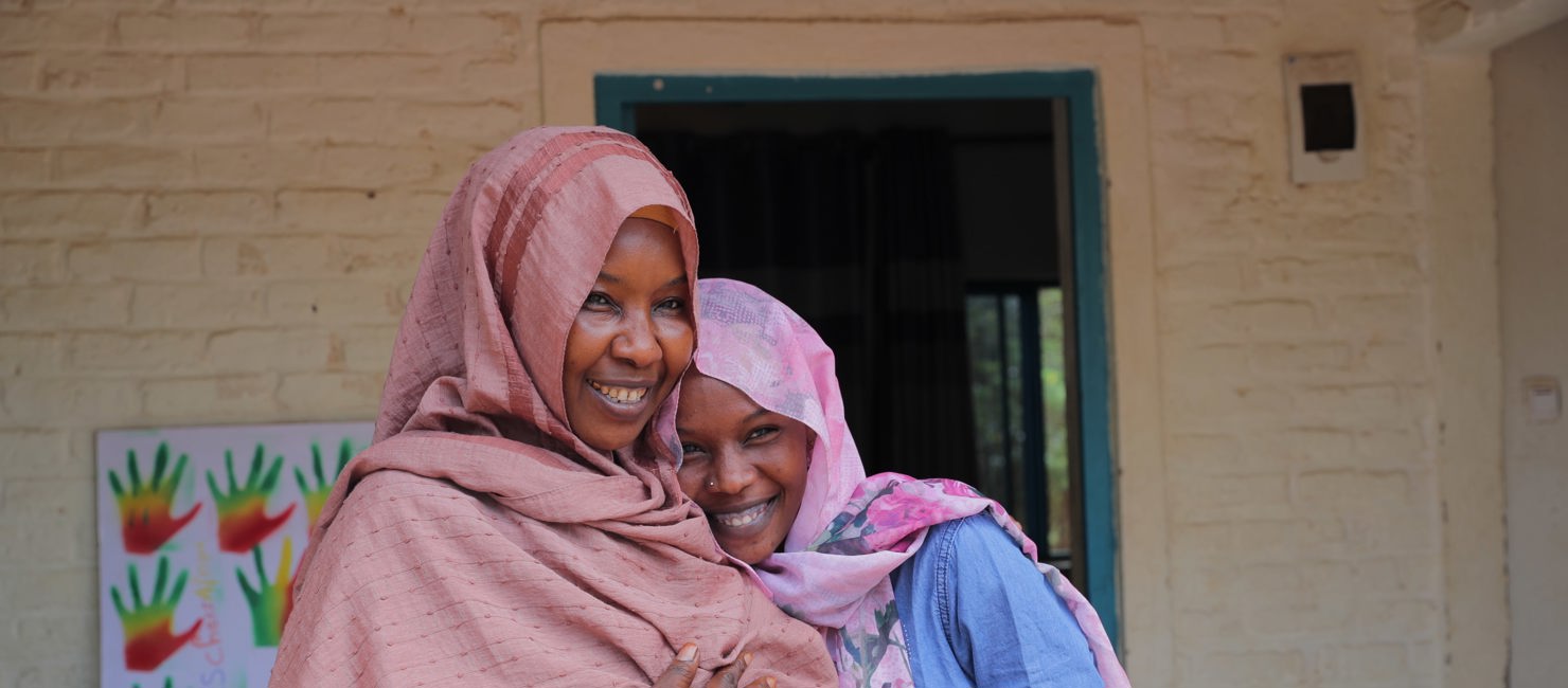 Raina and her daughter Fatima in front of their home at ETM Gashora. ETM Gashora was established in 2019 following the signature of a Memorandum of Understanding (MoU) by the Government of Rwanda, UNHCR and the African Union to rescue refugees and asylum-seekers from Libya, while continuing to search for durable solutions.
