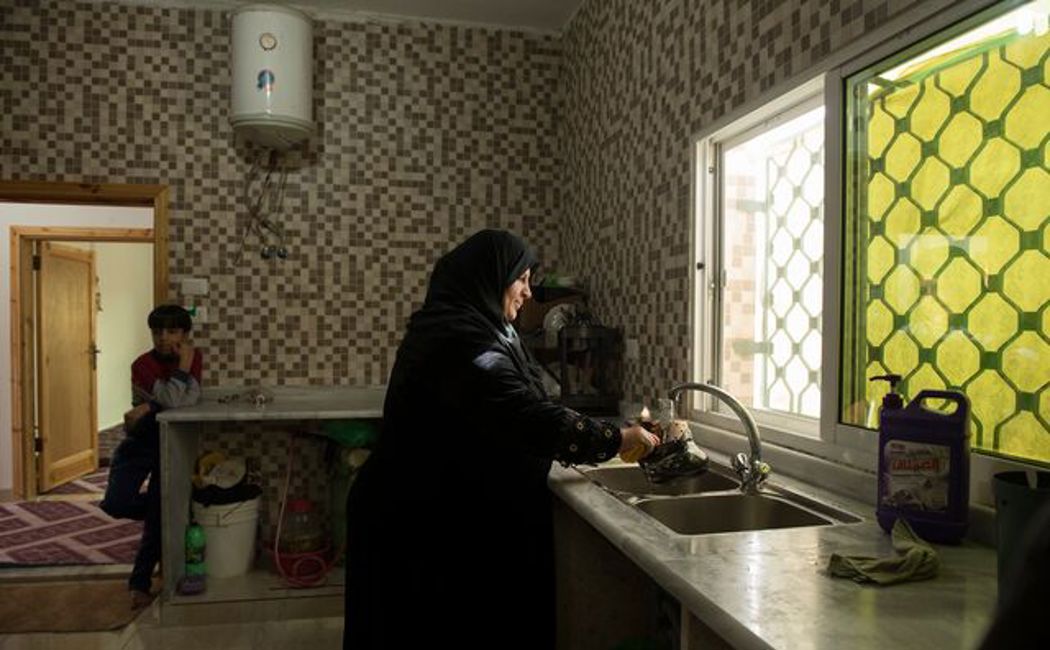 Nahlah washes dishes at home in her apartment in Mafraq, Jordan.