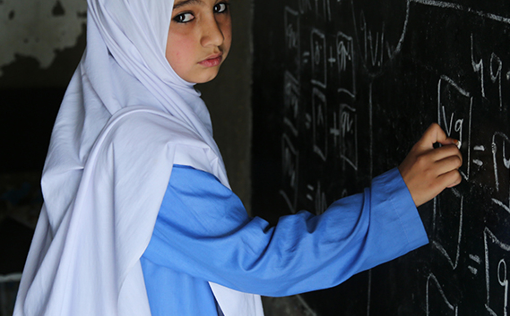 9 year old Mariam draws on a chalkboard at the UNHCR funded primary school for girls in Peshawar, Pakistan.