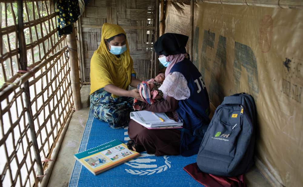  A community health volunteer helps Rohingya mothers with post natal care in Bangladesh.