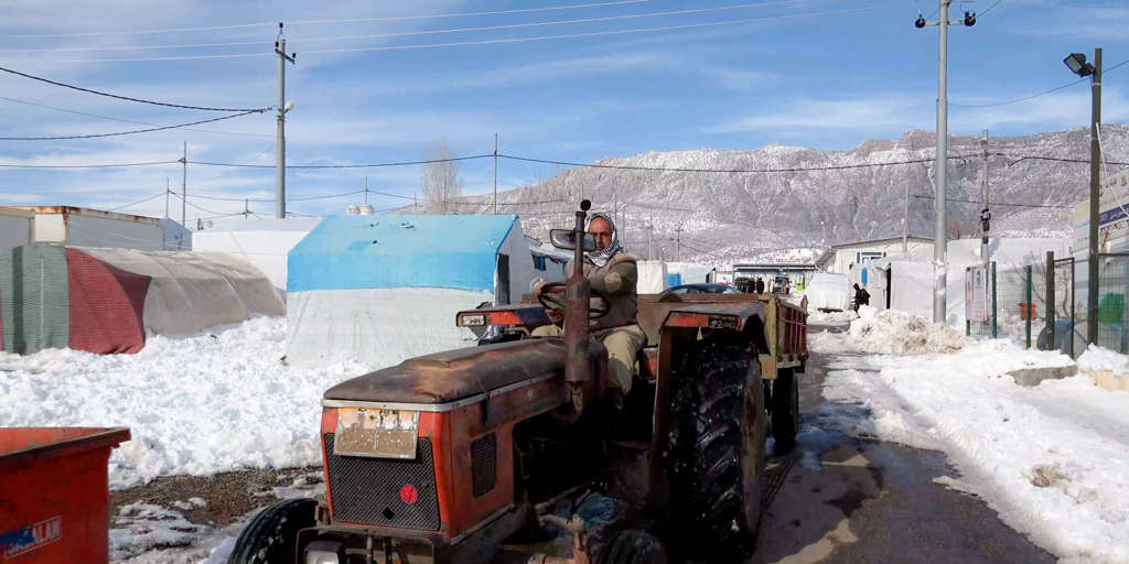 A worker uses a tractor to remove snow shovelled by residents from outside their shelters in Dawudiya camp for internally displaced people near Duhok in Iraqi Kurdistan.