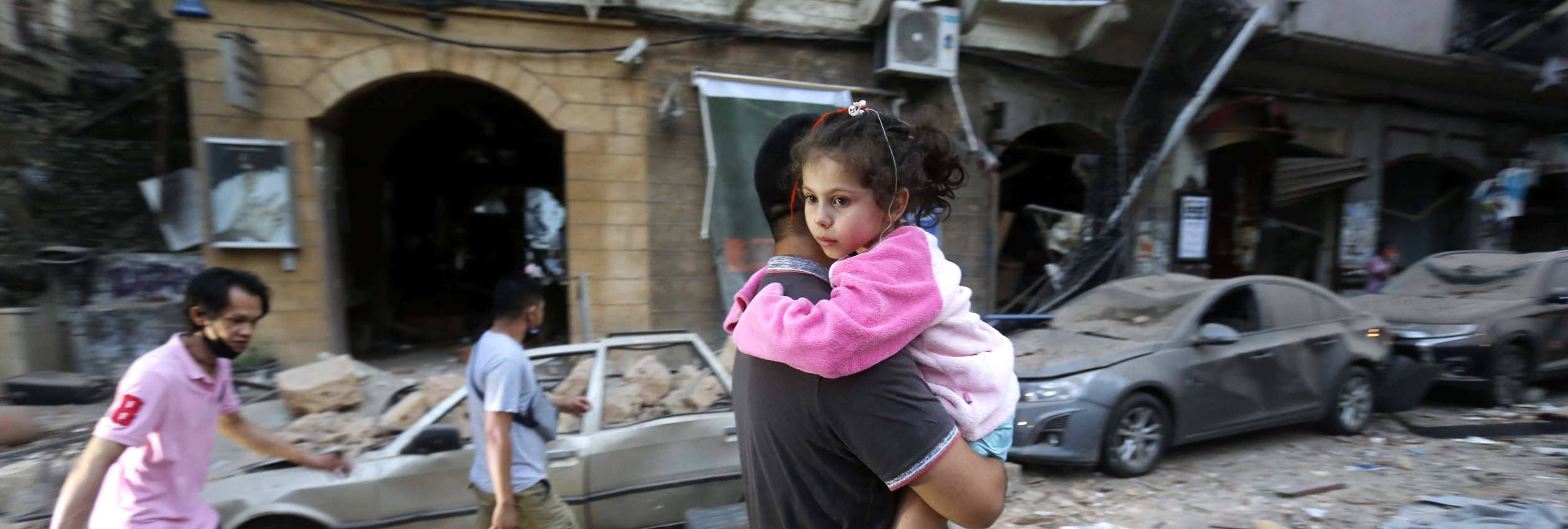 A man carries away an injured child on a street following an explosion in the Lebanese capital.