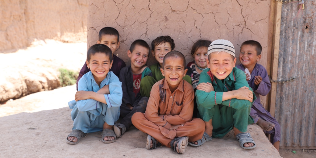 Afghan refugee children sitting and smiling in Islamabad