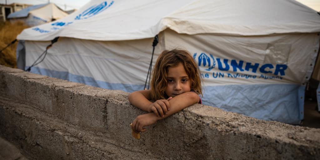 Eight-year-old Raghda Abbas Suleiman looks over a wall near her shelter at Bardarash camp in Duhok, Iraq, a day after arriving with her family.