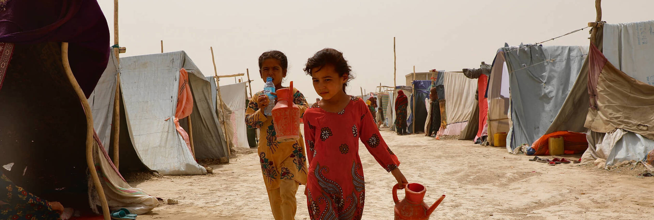 Children on their way out of the Nawabad Farabi-ha IDP camp as the wind and the dust blows though the camp.