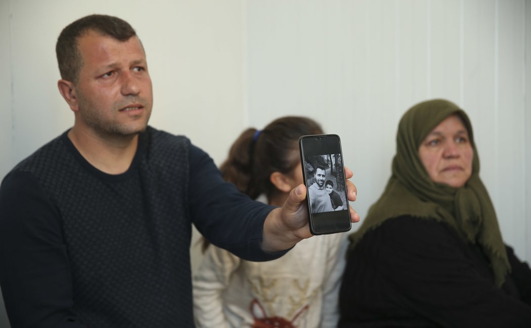 Ahmet Erkan, with his daughter and mother, shows a photograph of his brother and nephew who died when their building collapsed during the devastating February earthquakes.