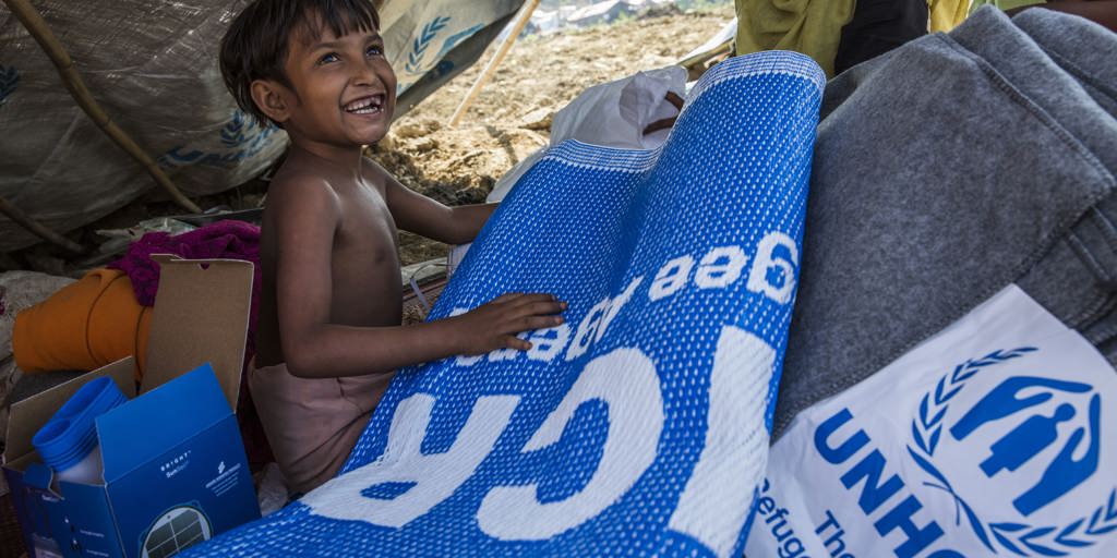 Rohingya mother Laila Begum, 30, and her children (from left) Aysha, 7, and Kishmot Ara, 5, receive their UNHCR Non-Food Items emergency relief pack in their makeshift shelter at Kutupalong refugee camp, Bangladesh.