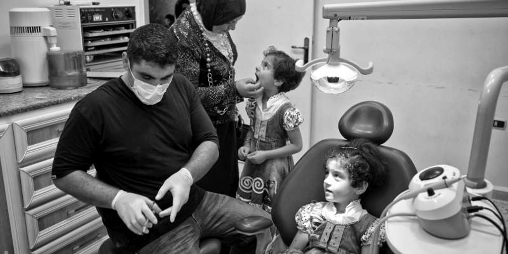 Dentist Hussam Kayed with patient Roha, aged seven years, in the Al Nahda Primary Health Care Clinic, to treat her teeth.