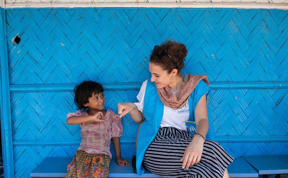 A young girl fist bumps a UNHCR staff member at a nutrition centre in a Rohingya refugee settlement, Cox’s Bazar, Bangladesh.