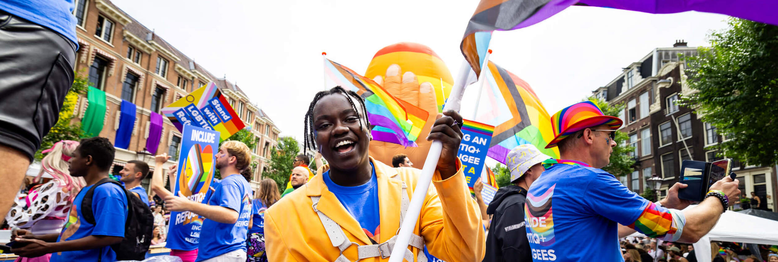 LGBTIQ+ refugees wave pride flags and hold up signs during a pride march in Amsterdam, The Netherlands