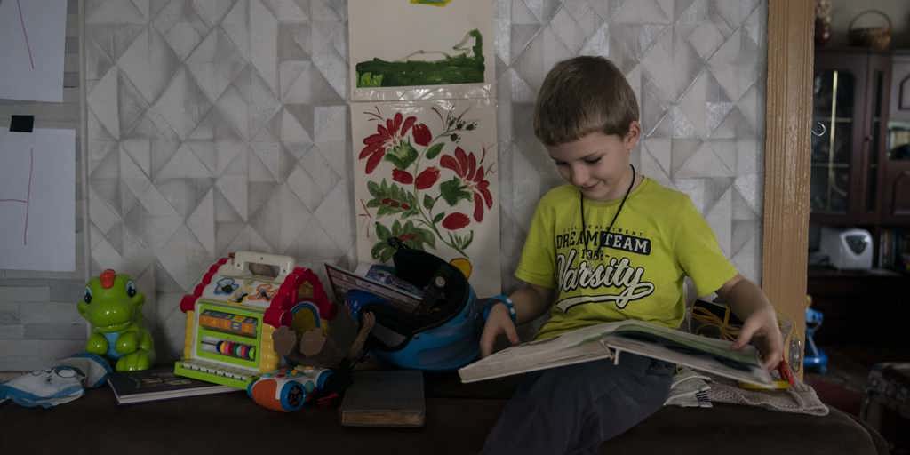 Ivan reads a book in his great grandparents' home in Kyiv, Ukraine. 