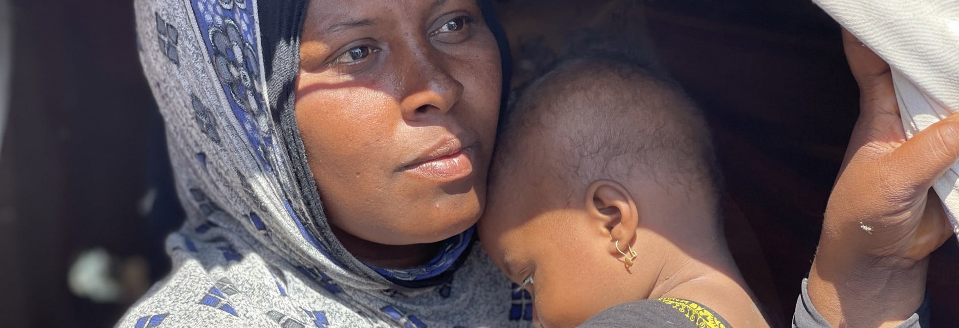 Internally displaced Yemeni mother, Lubna, holds her child after fleeing escalating fighting.