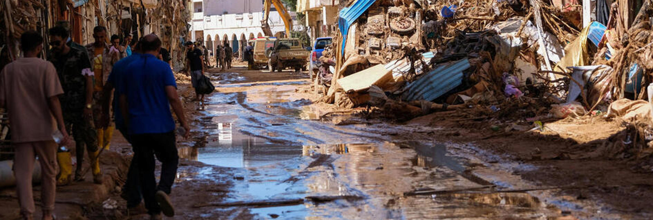 People walk in the mud between the rubbles, after a powerful storm and heavy rainfall hit Libya, in Derna, Libya September 13, 2023.