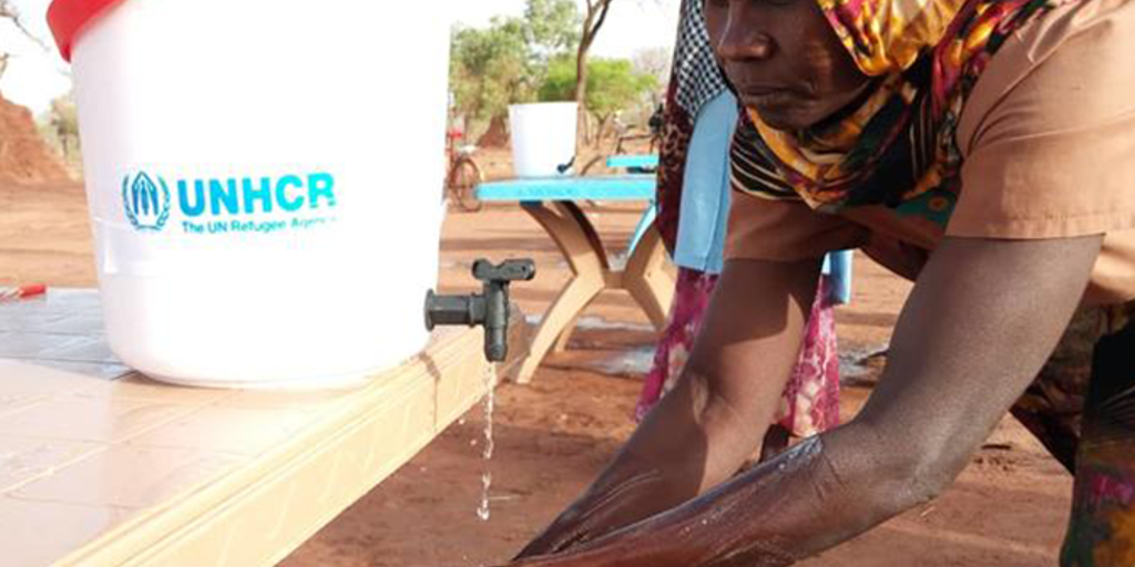 refugee washes hands at UNHCR sanitation station