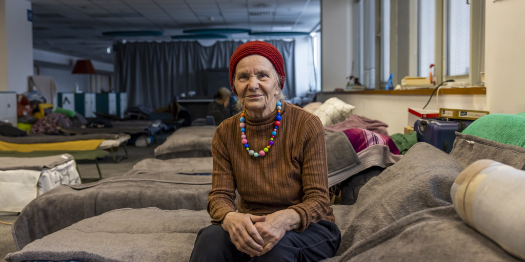 Valentina (83) is sitting on her bed posing at a collective centre in Kraków. 
