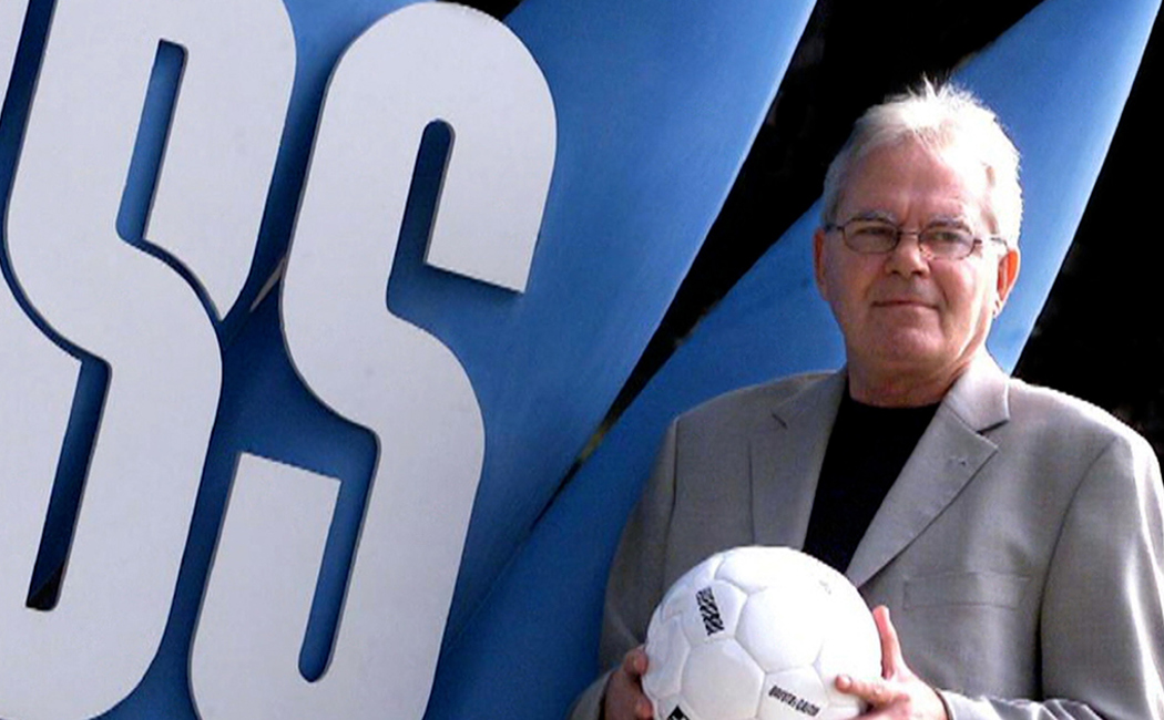 Les Murray AM holds a soccer ball in front of SBS signage © SBS