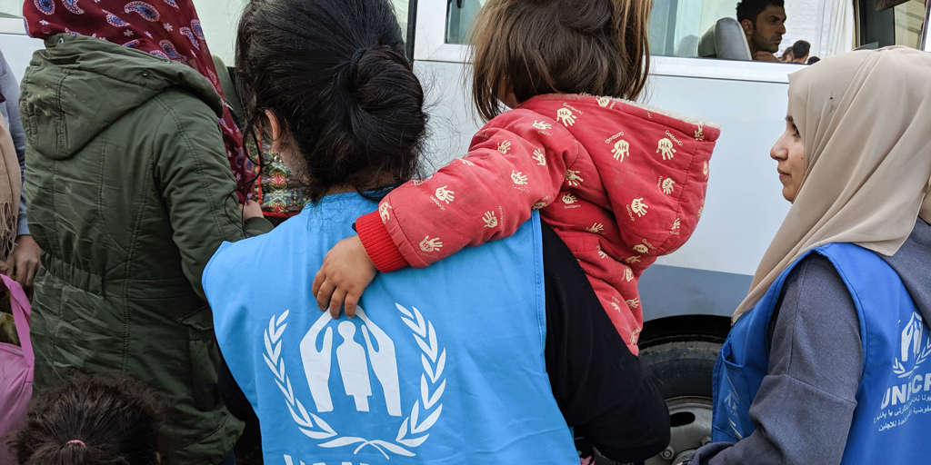 UNHCR staff member carries young child