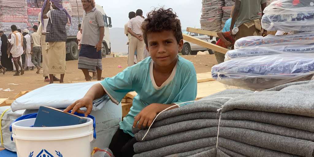 A displaced child from Hajjah sits near UNHCR provided supplies.