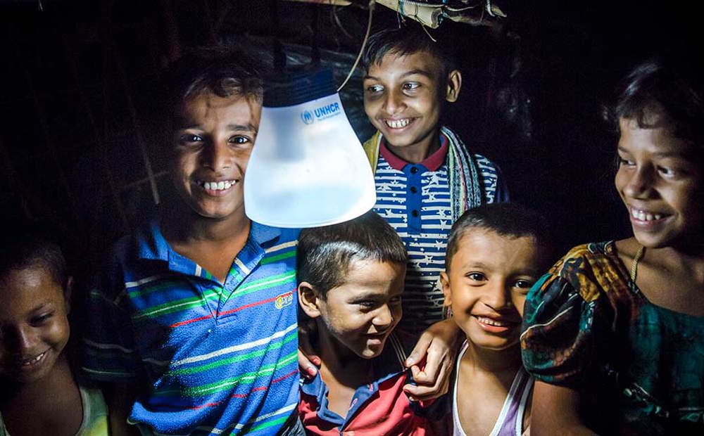 Young children in Bangladesh gather round a solar lamp at night | Ramadan charity gifts