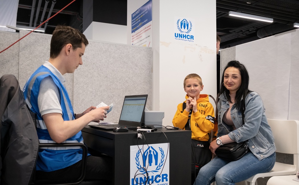 Yulia and her son wait at UNHCR's cash enrolment centre in Poland. They fled their home in Ukraine in March. 