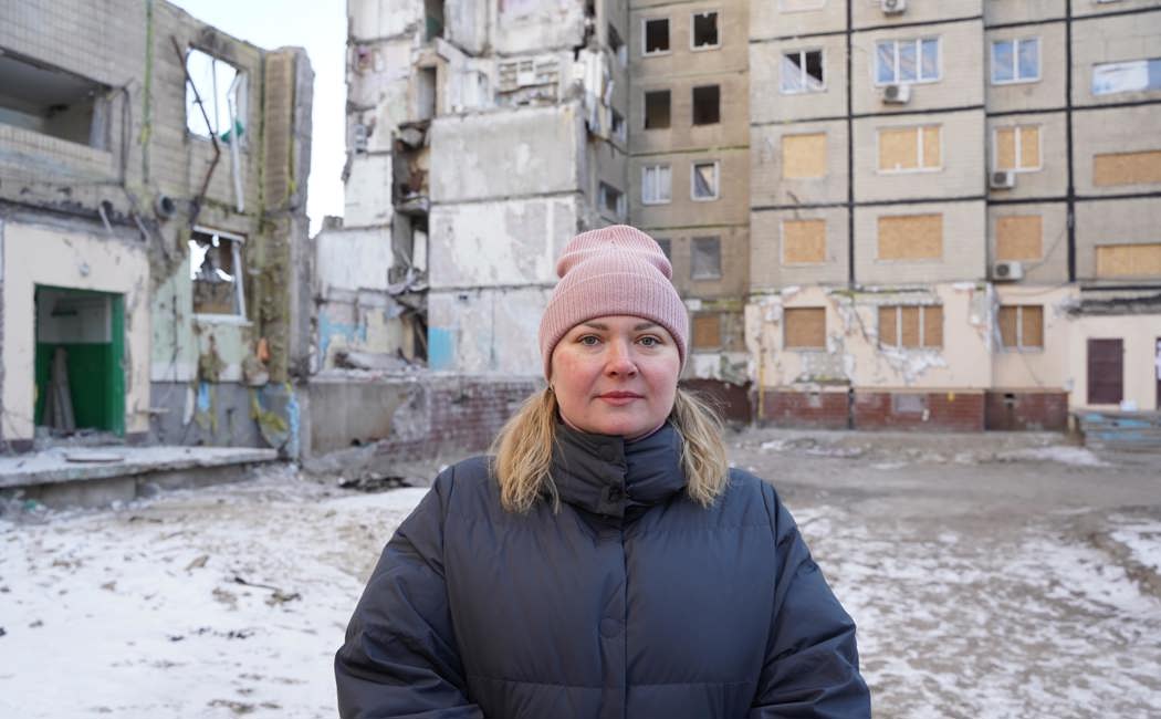 Anastasiya stands in front of her destroyed apartment building. 