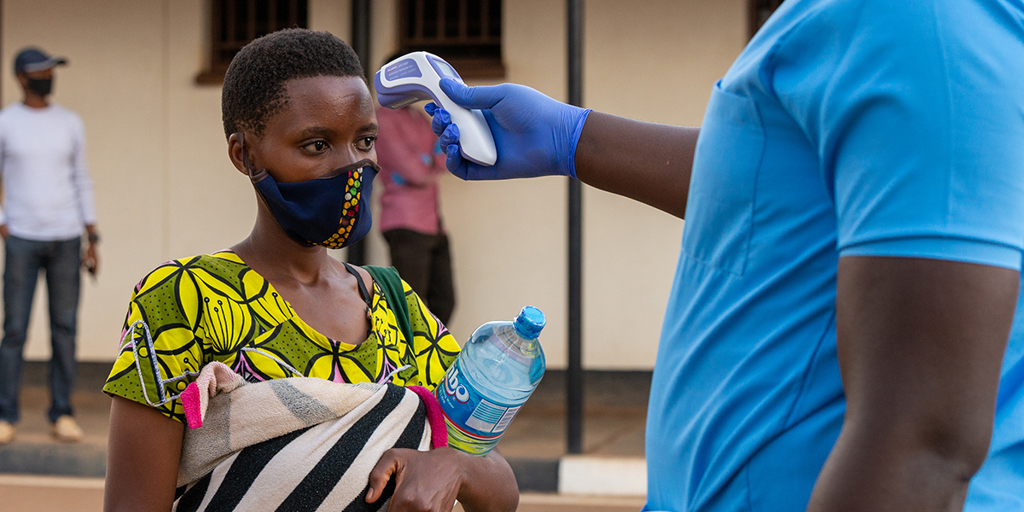 A Burundian refugee at Mahama camp has her temperature taken for signs of COVID-19 symptoms, as UNHCR staff facilitate the voluntary return from Rwanda. @UNHCR/Eugene Sibomana