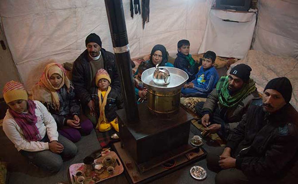 A family gather round a gas stove at night to keep warm | Ramadan charity gifts