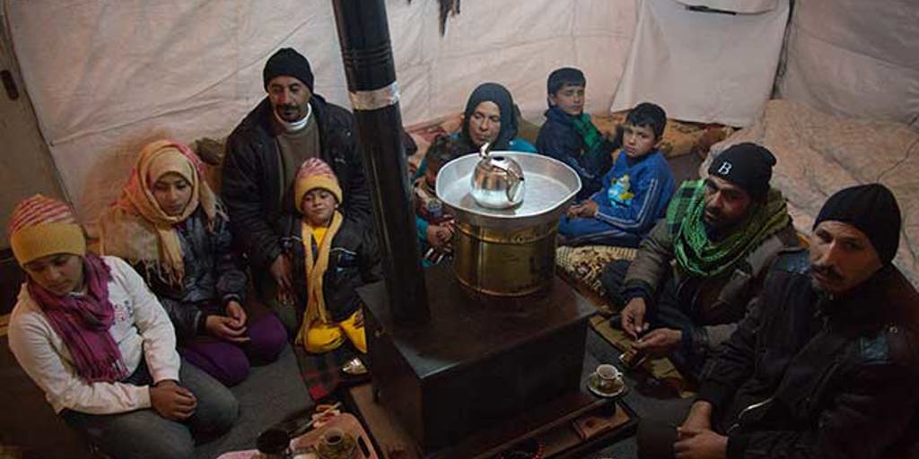 A family gather round a gas stove at night to keep warm | Ramadan charity gifts