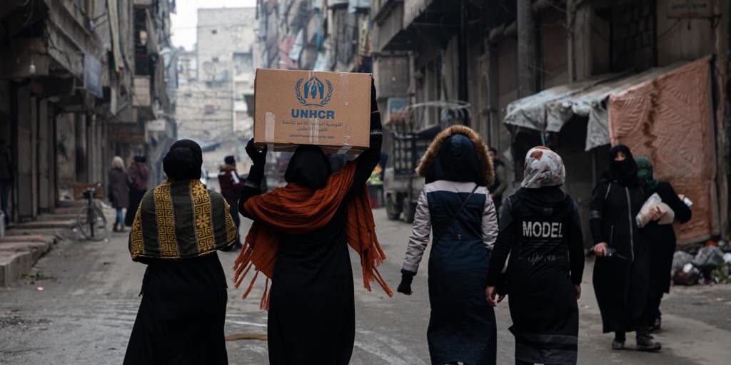 Women walking with UNHCR box. UNHCR distributes solar lights to female-headed families in Aleppo region, Syria.