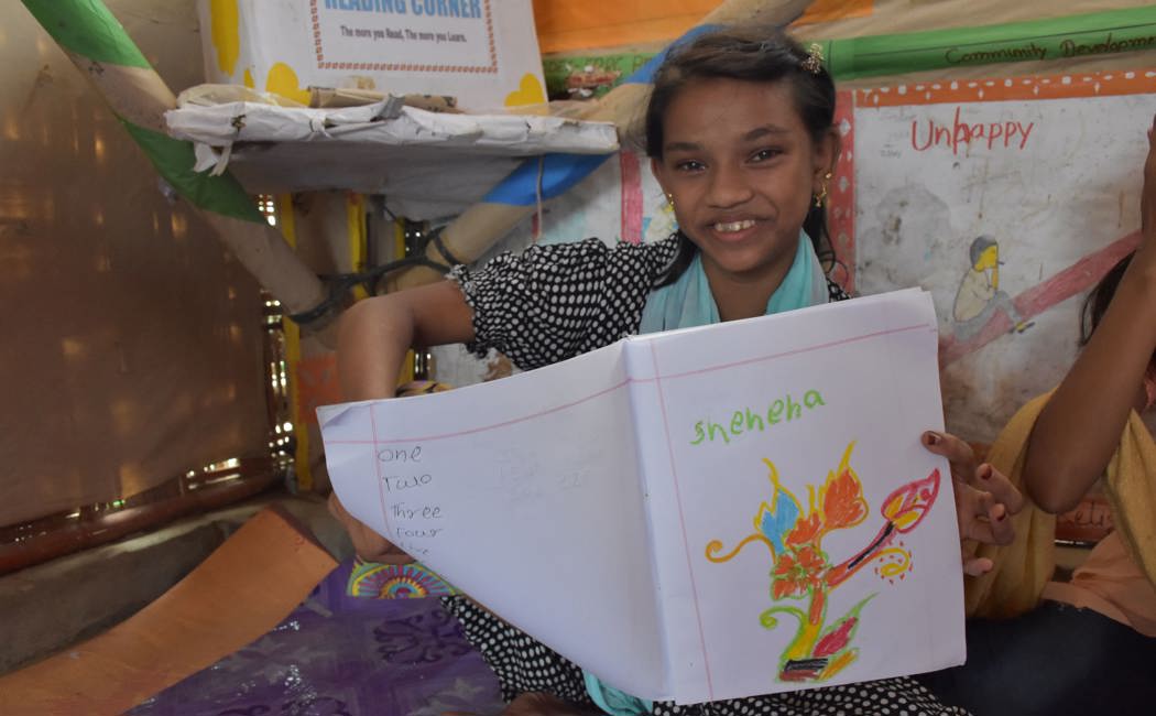 Shehana, Rohingya refugee holds artwork. She studies at the Diamond Adolescent Club set up by UNHCR partner.