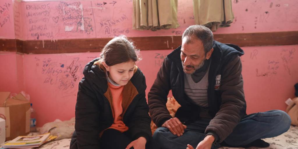 Father-of-three Adnan teaches his daughter Elisia schoolwork at the Mahmoud Saleh school shelter in Jableh city, Latakia Governorate, Syria