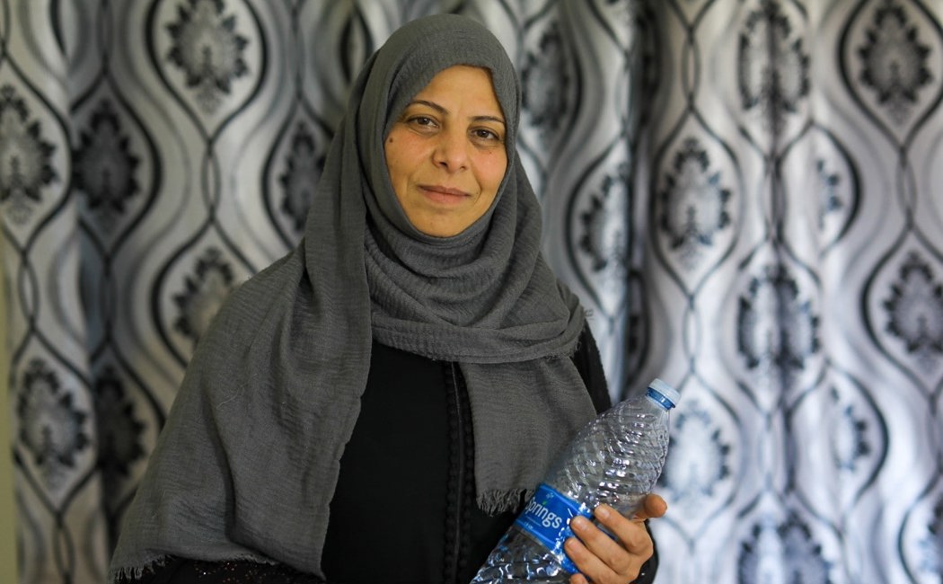 Syrian refugee Huda holds water bottle