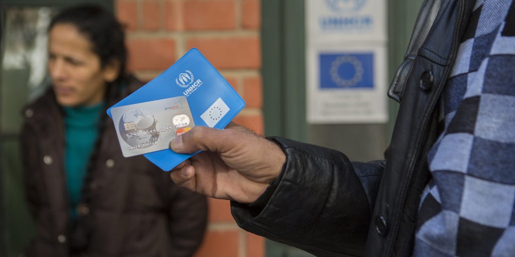 A man holds a UNHCR pouch and credit card
