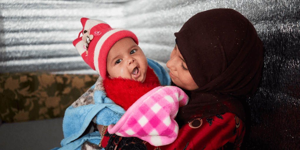 A Syrian mother with her child wrapped in blankets