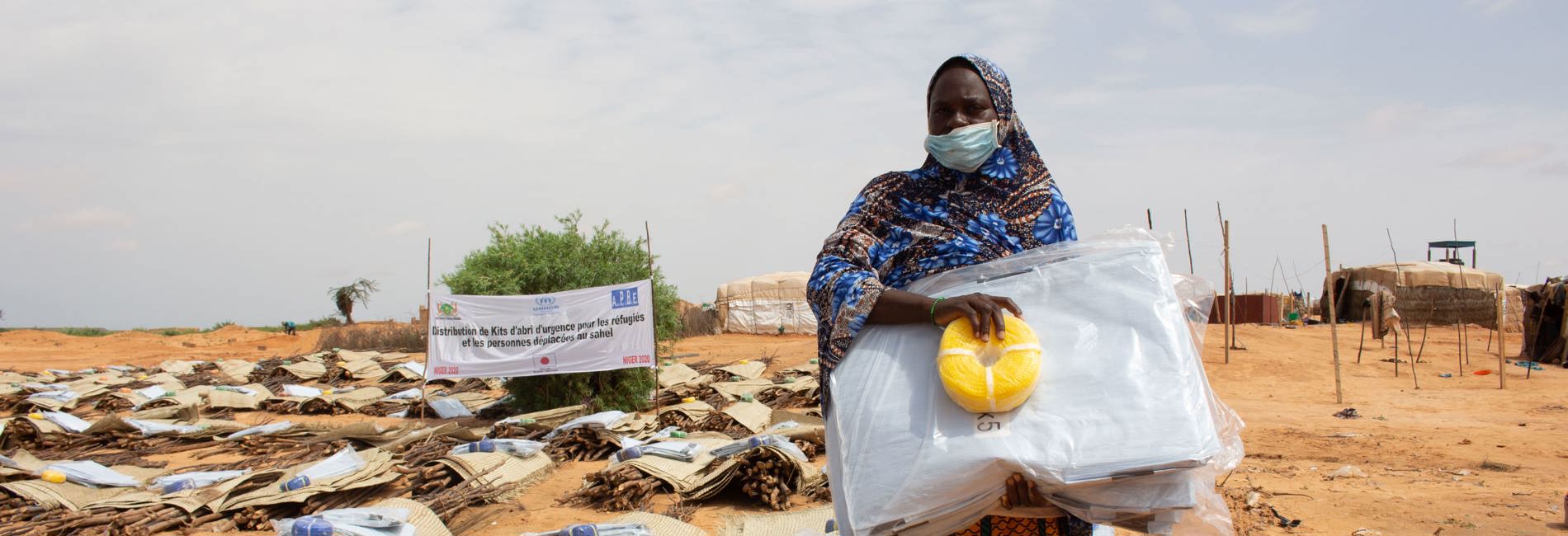 Woman standing with shelter kit. UNHCR emergency shelter kits help displaced persons in Niger.